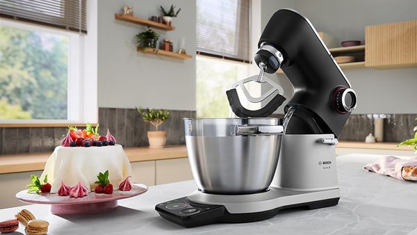 Robot da cucina Bosch con frusta, circondato da una torta e panna montata, per una cottura perfetta.