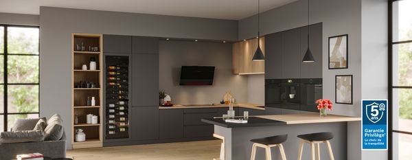 Cuisine moderne avec armoires noires et blanches, comptoirs en bois et éclairage pendentif. 