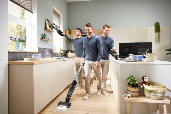Uomo che utilizza diverse configurazioni di un aspirapolvere convertibile Bosch Flexxo per pulire la cucina