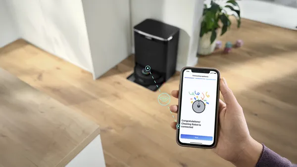 robot sprzatajacy, dlon trzymajaca smartfon