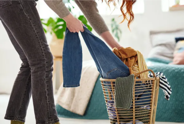 אישה מושכת ג'ינס מתוך סל כביסה מלא בגדים