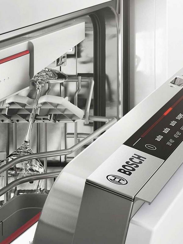 Gros plan sur un lave-vaisselle entrouvert. On y voit le bandeau de commande sur la tranche et l'int&eacute;rieur, avec un verre dans le panier sup&eacute;rieur.