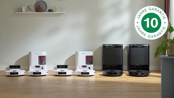 Vier Bosch Saugroboter in Weiß und Schwarz, auf einem Holzboden präsentiert, mit einem 10-Jahre-Garantie-Emblem in der Ecke.