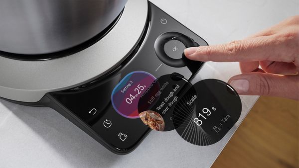 Ръка натиска бутона „OK“ на кухненска машина Серия 8, докато се показват различни настройки.