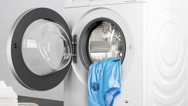 Lavatrice con oblò aperto e una maglia azzurra che sporge dal cestello.