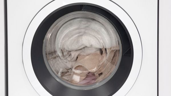 Lavatrice a carica frontale con asciugamani colorati all’interno.