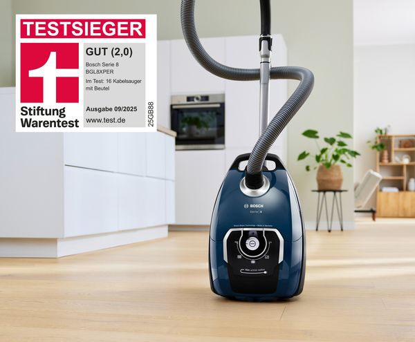 Ein blauer Serie 8 Beutelstaubsauger von Bosch steht auf dem Küchenboden und wurde mit der Bestnote GUT (2,0) alleiniger Testsieger der Stiftung Warentest 09/2025.