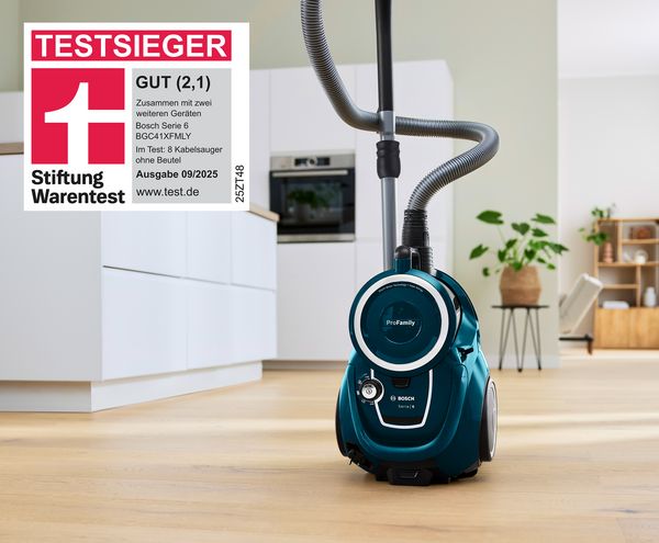 Ein blauer, beutelloser Serie 6 Staubsauger von Bosch steht auf dem Küchenboden und wurde mit der Bestnote GUT (2,1) Testsieger der Stiftung Warentest 09/2025.