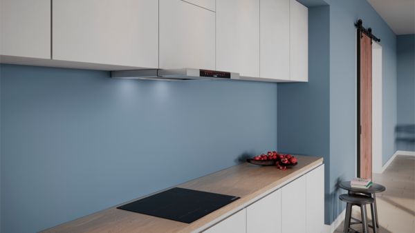 Модерна кухня с вграден готварски плот, аспиратор, синя стена и минималистичен декор.
