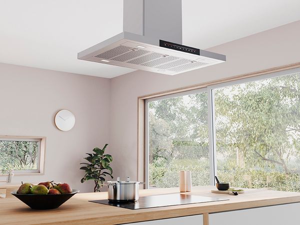 Модерна кухня с монтиран на тавана аспиратор над печка върху дървен кухненски остров.