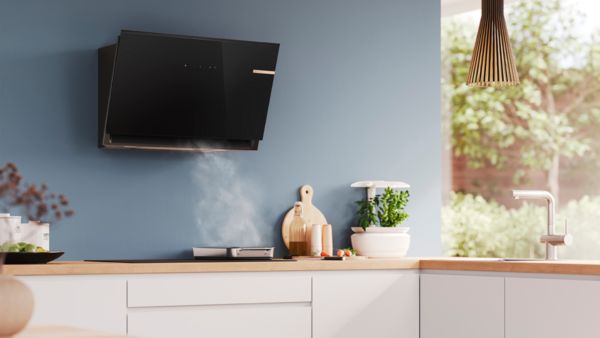 Модерна кухня с елегантен черен стенен аспиратор над печка и дървен плот.
