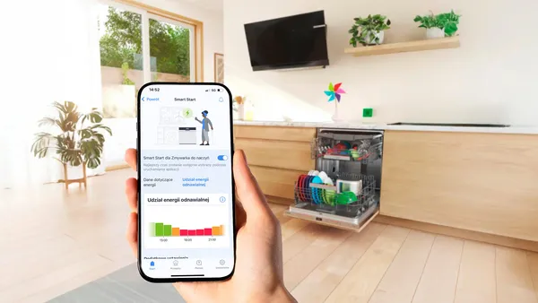 dlon trzymajajaca smartfon na tle kuchnia