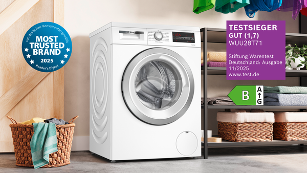 Eine Bosch Waschmaschine neben einem Regal mit Handtüchern.