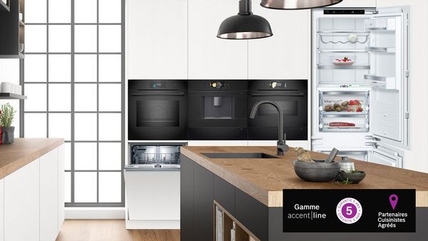 Cuisine ouverte blanche et bois, avec appareils électroménagers accent line noirs.