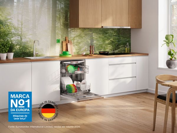 Vista total de uma cozinha com uma m&aacute;quina de lavar loi&ccedil;a aberta com um papel de parede de fundo de uma floresta verde e ensolarada.