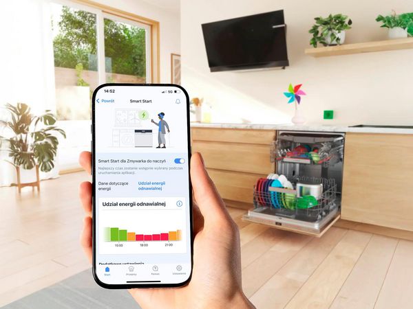 Dłon trzyma smartfon na tle zmywarka