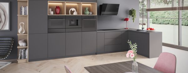 Stijlvolle inductieplaat van Bosch met koolzwarte matte afwerking. Op de kookplaat staat een braadslede met zalm.