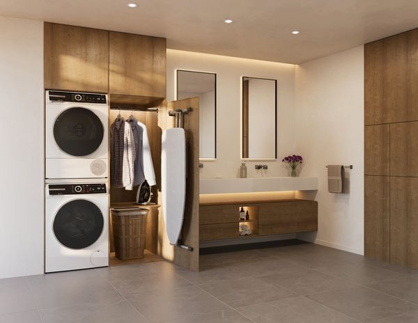 Lavanderia in bagno con lavatrice e asciugatrice Bosch a colonna, armadio con asse da stiro e lavabo in legno con specchi