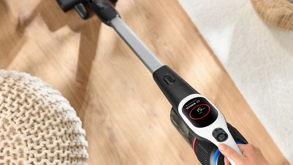 Es ist eine Hand zu sehen, die einen Unlimited 9 Akku-Staubsauger hält und damit einen Holzfußboden saugt.