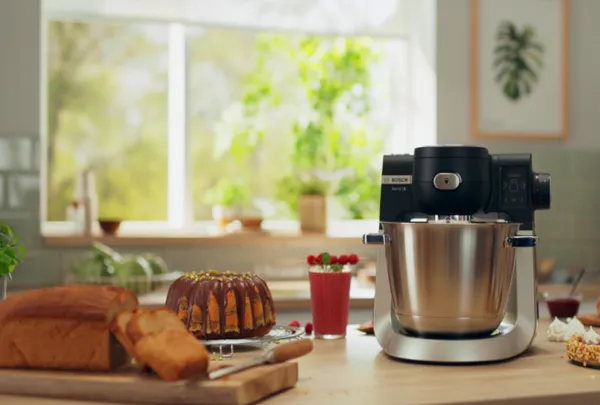 מיקסר של בוש מונח על שיש כשלצדו עוגות