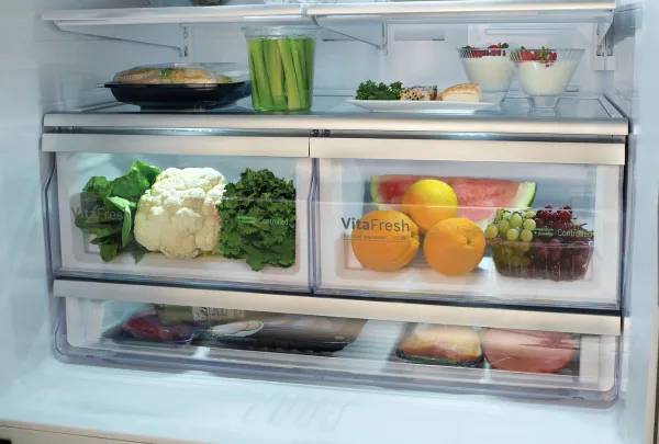 ירקות ופירות מונחים בתוך מגירה במקרר של בוש עם כיתוב VitaFresh על המגירות