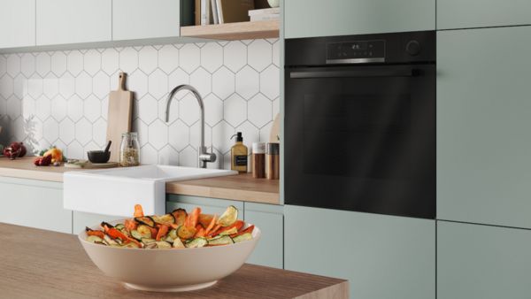 Built-in oven viewed within white cabinetry, displaying vibrant food cooking inside. 