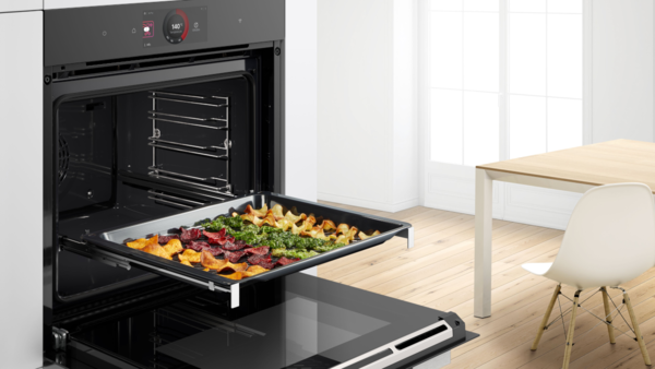 Offener Bosch Serie 8 Backofen mit herausgezogenem Air-Fry-Blech, belegt mit Gem&uuml;sechips; Darstellung der Air Fry Funktion f&uuml;r fettarmes, knuspriges Garen im Backofen.