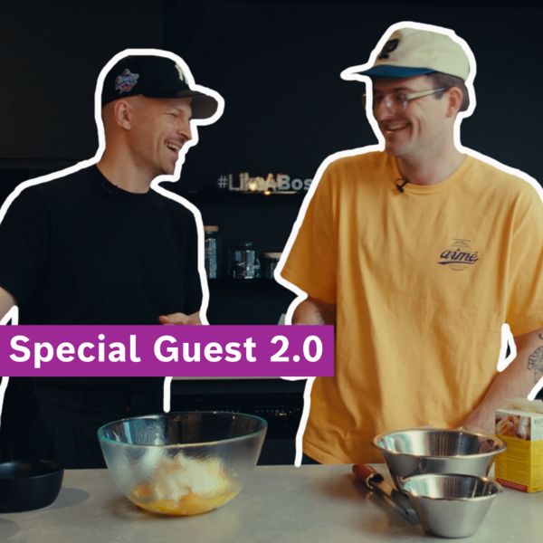 Mann benutzt Küchengerät und bereitet Essen zu, umgeben von Zutaten auf einem Holztisch.