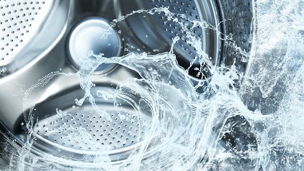 Bildet viser innsiden av en vaskemaskin, med vann rundt.