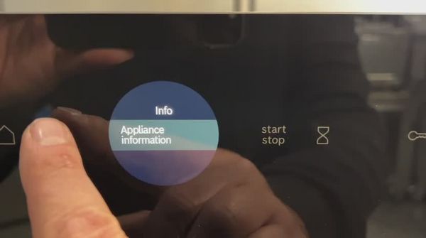 A close-up of a touchscreen displaying an "Appliance information" option being pressed, with start/stop buttons visible.