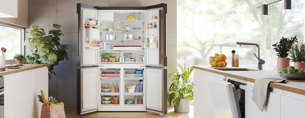 Moderne keuken met een zwarte koelkast, witte kasten, houten werkbladen en grote ramen voor natuurlijk licht. 