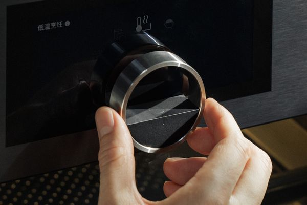 Close-up of a hand operating the floating dial of the Expressive series steam oven