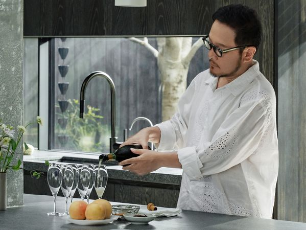 Wu Bin pouring drinks in his kitchen