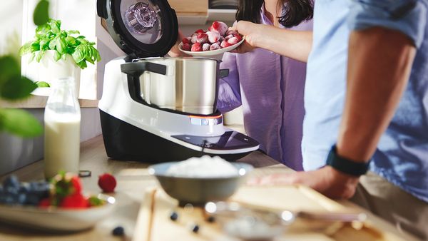 Bosch Cookit im Einsatz: Zwei Personen geben Zutaten in den Topf und bereiten gemeinsam ein Rezept zu.
