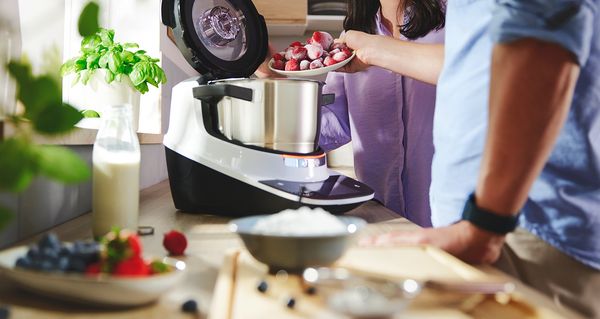 Bosch Cookit im Einsatz: Zwei Personen geben Zutaten in den Topf und bereiten gemeinsam ein Rezept zu.