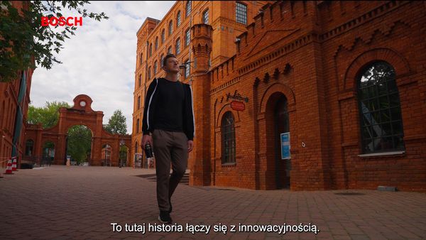 Mezczyzna idzie ulica na tle ceglastych budynkow