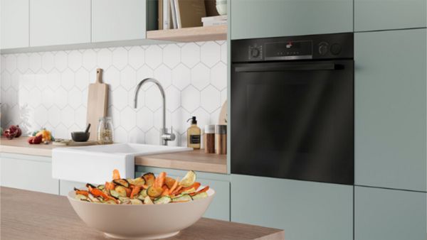 Moderne K&uuml;che mit wei&szlig;en Schr&auml;nken, schwarzen Ger&auml;ten und Holzakzenten.