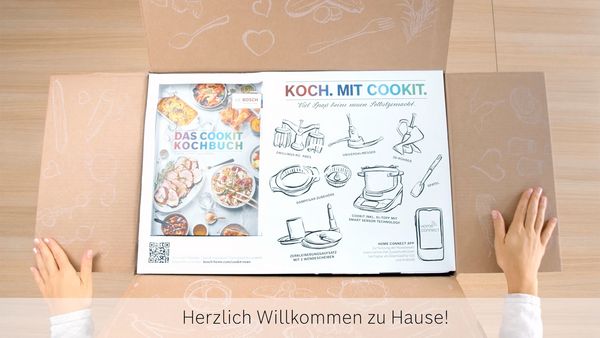 Ge&ouml;ffnete Cookit Verpackung mit Kochbuch, Zubeh&ouml;r&uuml;bersicht und Willkommen-Hinweis f&uuml;r den Start mit dem Bosch Cookit.