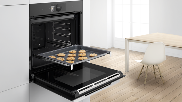 Bosch sobasının qapısı a&ccedil;ıqdır; təzə bişmiş pe&ccedil;enyelərlə dolu bir tepsi &ccedil;ıxarılır.