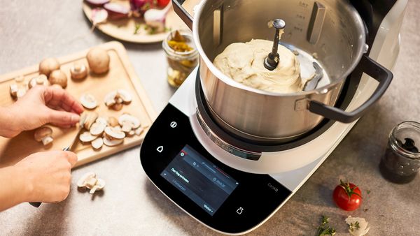 Bosch Cookit im Einsatz beim R&uuml;hren einer Masse mit eingesetztem R&uuml;hrwerk, Zutaten werden auf der Arbeitsfl&auml;che vorbereitet.