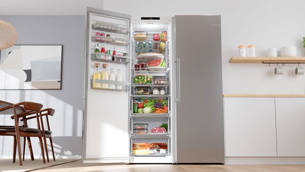 Отворен, модерен side-by-side хладилник в стилна кухня, показващ пресни продукти, напитки и организирани отделения.