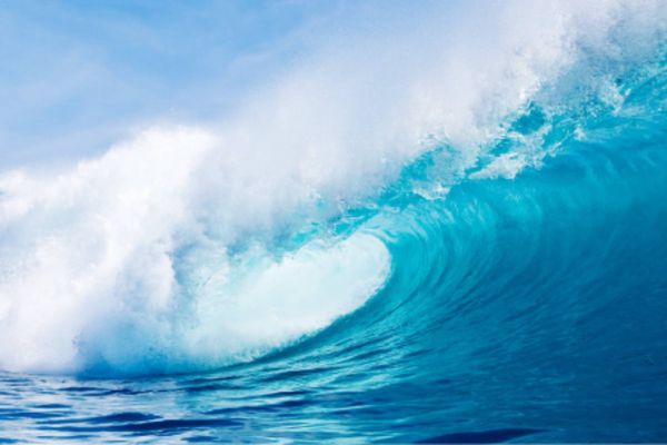 A huge wave of sparkling blue water is about to break
