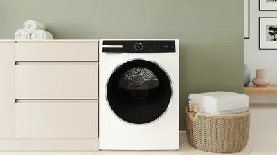 Pračka v pr&aacute;delně s ručn&iacute;ky na komodě vedle umyvadla.