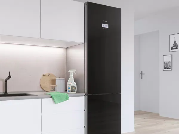 Modern kitchen with a black fridge and Bosch Fridge Cleaner spray and green cloth on the countertop.