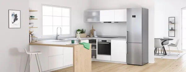 Bright kitchen scene with a stainless-steel refrigerator; Bosch Fridge Cleaner spray bottle and a green cloth placed on the island, ready for cleaning.
