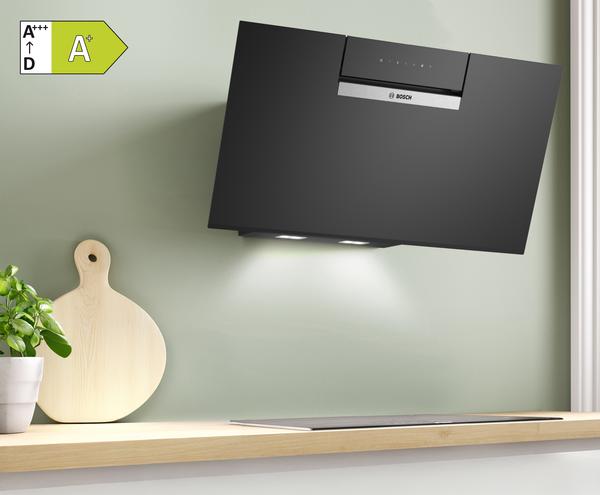 Schwarze BOSCH Kopffreihaube in einer hellen K&uuml;che, daneben ein Holzschneidebrett.
