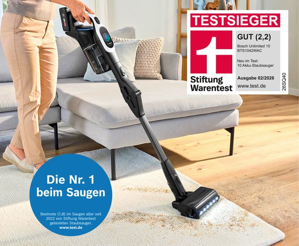 Eine Person reinigt mit dem Bosch Akku-Staubsauger Unlimited 10 BTS1042WAC (Testsieger der Stiftung Warentest) einen Teppich.
