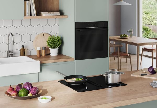 Bilden visar ett gr&ouml;nt k&ouml;k med en inbyggnadsugn (HRG4720B3) fr&aring;n Bosch.