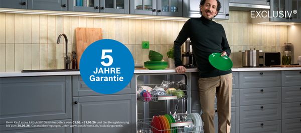 Person r&auml;umt sauberes Geschirr aus einem Geschirrsp&uuml;ler in einer modernen K&uuml;che ein.