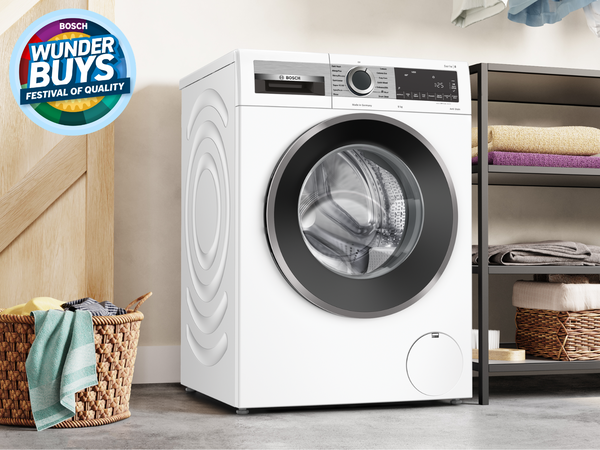 Bosch front-load washing machine in a bright laundry with wicker basket and shelving.  